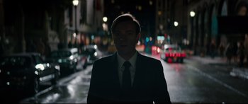 Movie still from “American Pastoral” (2016), directed by Ewan McGregor – A man wearing a suit and tie standing in the middle of a street; Medium shot, Low angle