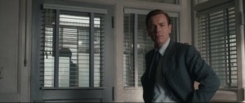 Movie still from “American Pastoral” (2016), directed by Ewan McGregor – A man standing in front of a window in a room; Medium shot, Low angle