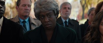 Movie still from “American Pastoral” (2016), directed by Ewan McGregor – An older woman with gray hair is looking at the camera; Close Up shot, Over the shoulder angle