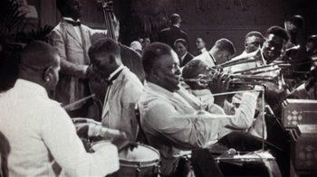 Movie still from “American Pop” (1981), directed by Ralph Bakshi – A black and white photo of a group of men playing musical instruments; Medium shot, High angle