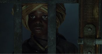 Movie still from “Amistad” (1997), directed by Steven Spielberg – A young boy with a turban is behind bars; Close Up shot, Low angle