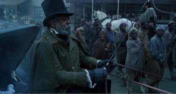 Movie still from “Amistad” (1997), directed by Steven Spielberg – An old man in a top hat sitting in front of a group of people; Medium shot, Over the shoulder angle