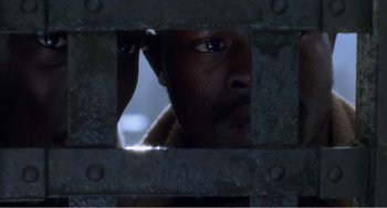 Movie still from “Amistad” (1997), directed by Steven Spielberg – A person's face through a fence; Close Up shot, High angle