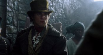 Movie still from “Amistad” (1997), directed by Steven Spielberg – A man wearing a hat and glasses in a forest; Medium shot, Low angle