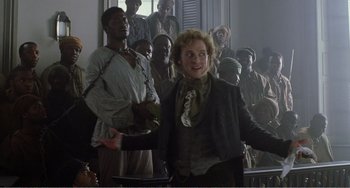 Movie still from “Amistad” (1997), directed by Steven Spielberg – A man and a woman standing next to each other in front of a group of people; Medium shot, Over the shoulder angle