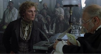 Movie still from “Amistad” (1997), directed by Steven Spielberg – A man sitting in front of a group of people; Medium shot, Over the shoulder angle