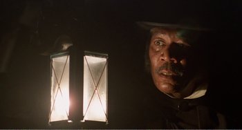 Movie still from “Amistad” (1997), directed by Steven Spielberg – A man with a mustache and a hat standing in front of a lamp; Close Up shot, Low angle