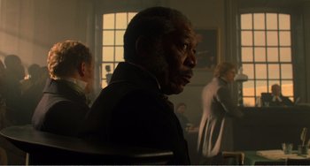 Movie still from “Amistad” (1997), directed by Steven Spielberg – An older man sitting in front of a group of people; Medium shot, Over the shoulder angle