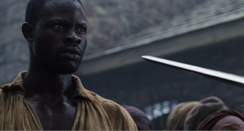 Movie still from “Amistad” (1997), directed by Steven Spielberg – A black man with a knife in his hand; Close Up shot, Over the shoulder angle