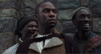 Movie still from “Amistad” (1997), directed by Steven Spielberg – A man wearing a brown and white jacket looking to his left; Close Up shot, Low angle