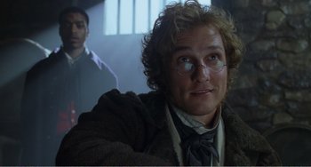 Movie still from “Amistad” (1997), directed by Steven Spielberg – A person wearing glasses and a coat; Close Up shot, Over the shoulder angle