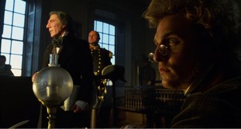 Movie still from “Amistad” (1997), directed by Steven Spielberg – A man in a suit and tie sitting in front of another man in a suit and tie; Close Up shot, Low angle