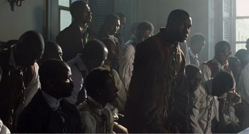Movie still from “Amistad” (1997), directed by Steven Spielberg – A group of men sitting next to each other in a room; Wide shot, High angle