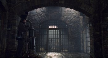 Movie still from “Amistad” (1997), directed by Steven Spielberg – An open door leading to a jail cell with bars; Extreme Wide shot, High angle