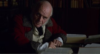 Movie still from “Amistad” (1997), directed by Steven Spielberg – An old man sitting at a table reading a book; Close Up shot, Over the shoulder angle