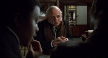 Movie still from “Amistad” (1997), directed by Steven Spielberg – An older man sitting in front of a younger man; Close Up shot, Over the shoulder angle