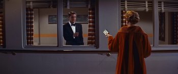 Movie still from “An Affair to Remember” (1957), directed by Leo McCarey – A person taking a picture of a man in a tuxedo in front of a mirror; Medium shot, Low angle