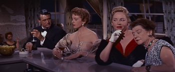 Movie still from “An Affair to Remember” (1957), directed by Leo McCarey – Two women sitting at a table with a glass of wine; Medium shot, Over the shoulder angle