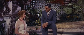 Movie still from “An Affair to Remember” (1957), directed by Leo McCarey – A man and a woman sitting on the ground in front of bushes; Medium shot, Over the shoulder angle
