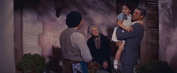 Movie still from “An Affair to Remember” (1957), directed by Leo McCarey – An older woman in a black dress is talking to a group of people; Medium shot, Low angle