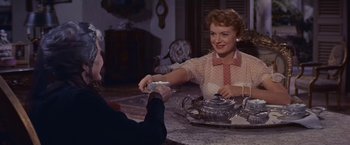 Movie still from “An Affair to Remember” (1957), directed by Leo McCarey – A woman sitting at a table with a tea pot in front of a man; Medium shot, Over the shoulder angle