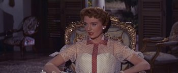 Movie still from “An Affair to Remember” (1957), directed by Leo McCarey – A woman sitting in a chair wearing a polka dot shirt; Medium shot, Low angle