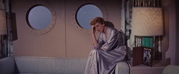 Movie still from “An Affair to Remember” (1957), directed by Leo McCarey – A woman sitting in front of a porthole window; Medium shot, High angle