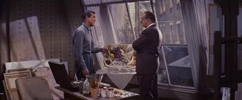 Movie still from “An Affair to Remember” (1957), directed by Leo McCarey – Two men in a room , one holding a basket of fruit and the other holding a painting; Medium shot, Over the shoulder angle