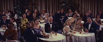 Movie still from “An Affair to Remember” (1957), directed by Leo McCarey – A group of people sitting at a table with drinks; Wide shot, High angle