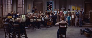 Movie still from “An Affair to Remember” (1957), directed by Leo McCarey – A group of people sitting in a room with musical instruments; Wide shot, High angle