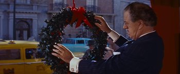 Movie still from “An Affair to Remember” (1957), directed by Leo McCarey – A man in a suit and tie holding a wreath; Close Up shot, Over the shoulder angle