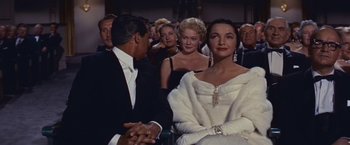 Movie still from “An Affair to Remember” (1957), directed by Leo McCarey – A man and a woman sitting in front of other people; Medium shot, Over the shoulder angle