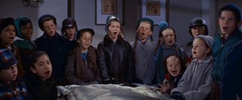 Movie still from “An Affair to Remember” (1957), directed by Leo McCarey – A group of young children singing in front of a bed; Medium shot, High angle