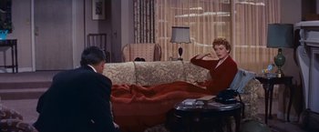 Movie still from “An Affair to Remember” (1957), directed by Leo McCarey – A man and a woman sitting on a couch in a living room; Wide shot, High angle
