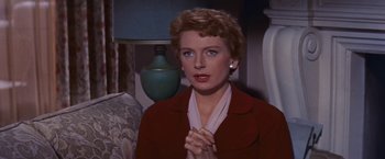 Movie still from “An Affair to Remember” (1957), directed by Leo McCarey – A woman in a red jacket clasps her hands; Close Up shot, High angle