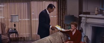 Movie still from “An Affair to Remember” (1957), directed by Leo McCarey – A man in a suit is handing bananas to a woman; Medium shot, Low angle