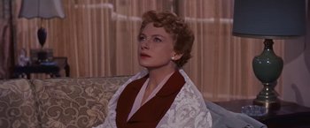 Movie still from “An Affair to Remember” (1957), directed by Leo McCarey – A woman sitting on top of a couch in a living room; Close Up shot, Low angle