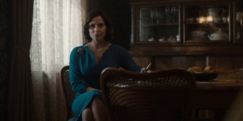 Movie still from “Dark” (2017), created by Baran bo Odar – A woman in a blue dress sitting in a chair; Medium shot, Over the shoulder angle