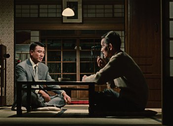 Two men sitting on a bench in front of each other
