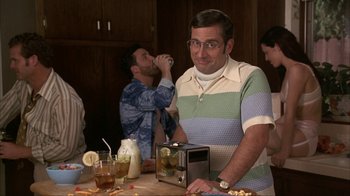 Movie still from “Anchorman: The Legend of Ron Burgundy” (2004), directed by Adam McKay – A group of people sitting at a table with drinks; Medium shot, Over the shoulder angle