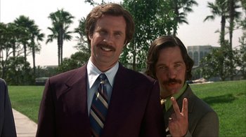 Movie still from “Anchorman: The Legend of Ron Burgundy” (2004), directed by Adam McKay – Two men dressed in suits and ties posing for a picture; Medium shot, Low angle