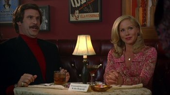 Movie still from “Anchorman: The Legend of Ron Burgundy” (2004), directed by Adam McKay – A man and a woman sitting at a table; Medium shot, Low angle