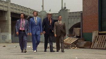 Movie still from “Anchorman: The Legend of Ron Burgundy” (2004), directed by Adam McKay – A group of men walking down a street; Wide shot, Low angle