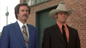 Movie still from “Anchorman: The Legend of Ron Burgundy” (2004), directed by Adam McKay – Two men in suits and hats standing next to each other; Close Up shot, Low angle