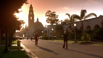 Two people walking down the street at sunset