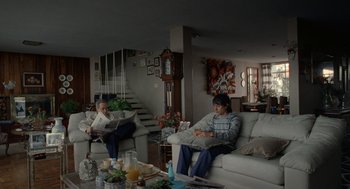 Movie still from “And Your Mother Too” (2001), directed by Alfonso Cuarón – Two people sitting on a couch in a living room; Wide shot, Low angle