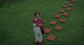 Movie still from “And Your Mother Too” (2001), directed by Alfonso Cuarón – A woman standing in the middle of a green field; Wide shot, High angle