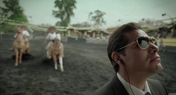 Movie still from “And Your Mother Too” (2001), directed by Alfonso Cuarón – A man wearing headphones while standing in a dirt field; Close Up shot, Over the shoulder angle