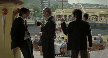 Movie still from “And Your Mother Too” (2001), directed by Alfonso Cuarón – A group of people standing around a table with drinks; Medium shot, Over the shoulder angle