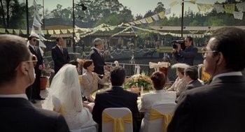 Movie still from “And Your Mother Too” (2001), directed by Alfonso Cuarón – A group of people sitting around a table at an outdoor event; Extreme Wide shot, Over the shoulder angle